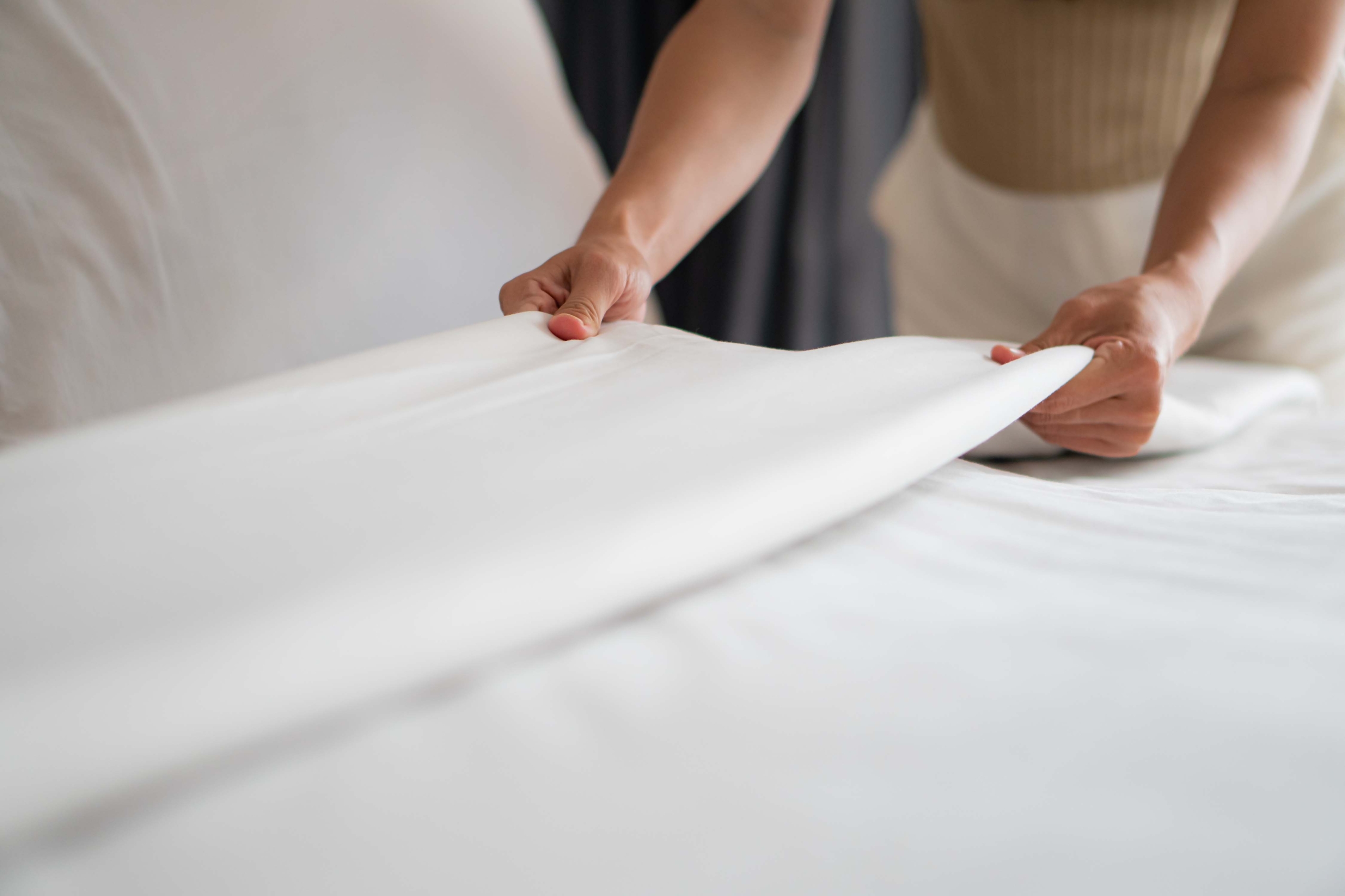 persona alisando la cama