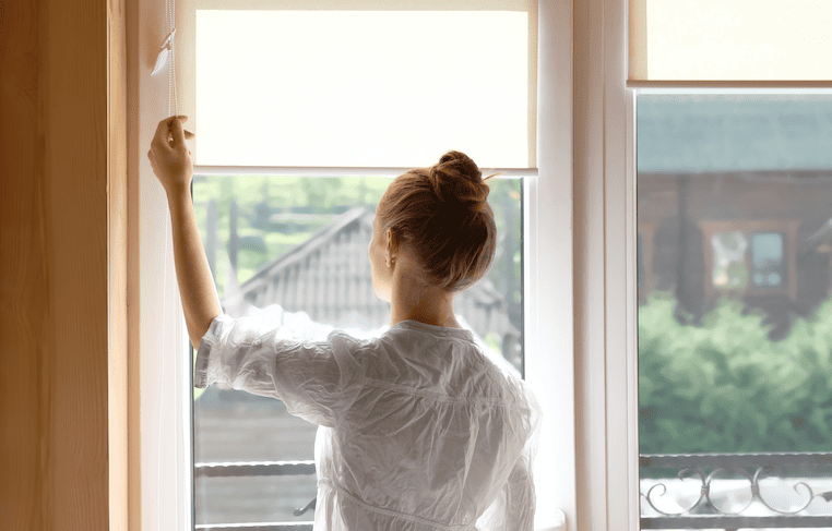 mujer bajando persianas refrescar la habitación en verano